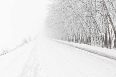 Winter road snowfall. An empty rural road without cars, covered with snowdrifts. Travel in bad...