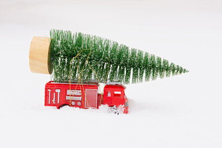 Car Christmas tree snow. Delivery of toys, New Year's mood, gifts on a red miniature children's car...