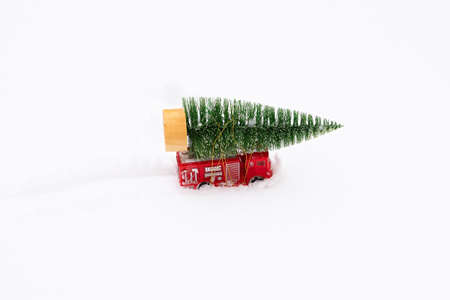 Car Christmas tree snow. Delivery of toys, New Year's mood, gifts on a red miniature children's car...