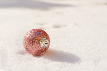 Christmas balls snow. Pink shiny Christmas decorations lie on the snow and sparkle. The concept of a holiday, gifts, congratulations. Horizontal snow banner in bright sunlight. Copy spaceの写真素材