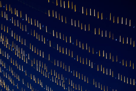 Abstraction blurred movement lights garlands. Golden lights of a blurred garland on the background of a purple blue sky. The concept of a night holiday night. Designer background of the New Year.の写真素材