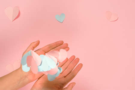 Paper pink hearts pastel pink background. A woman's hands throw a lot of valentines into the air. The concept of Valentine's Day, romance, confessions of feelings. Creative postcard design, copy spaceの写真素材
