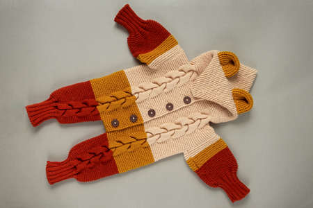 Knitted clothes color background. Handmade children's clothing. Knitted suit top view flat...