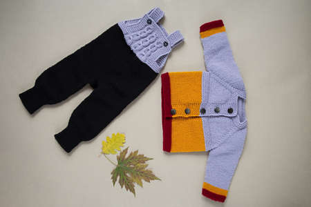 Knitted clothes color background. Handmade children's clothing. Knitted suit top view flat composition. The concept of hobby, individual marketing, entrepreneurship. Autumn time is cozy and warm.の写真素材