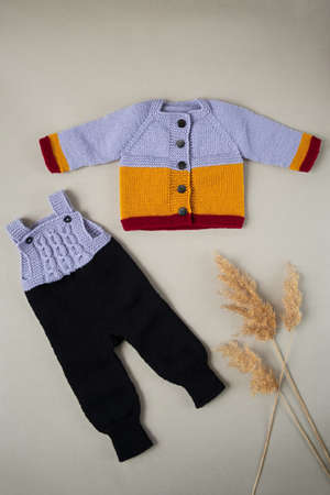 Knitted clothes color background. Handmade children's clothing. Knitted suit top view flat composition. The concept of hobby, individual marketing, entrepreneurship. Autumn time is cozy and warm.の写真素材