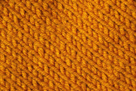 Knitted texture background. Hand-knitted wool. Macrophotography of a thread drawing. Orange bright texture of sweaters, pullovers, cardigans. Abstract natural background. Comfort autumn warmth conceptの写真素材
