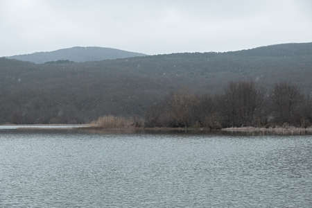 Lake grey landscape. A sad mood. Depression is a longing concept. Gray-blue autumn landscape. It's snowing through a hazy haze. Natural background. Beautiful silvery clouds. Journey to the lakeの写真素材