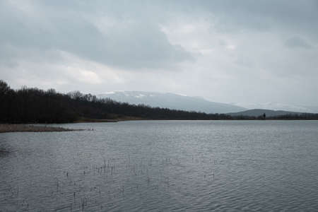 Lake grey landscape. A sad mood. Depression is a longing concept. Gray-blue autumn landscape. It's snowing through a hazy haze. Natural background. Beautiful silvery clouds. Journey to the lakeの写真素材