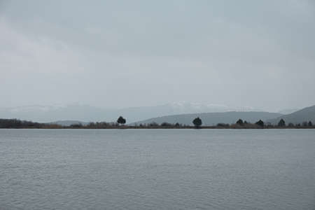 Lake grey landscape. A sad mood. Depression is a longing concept. Gray-blue autumn landscape. It's snowing through a hazy haze. Natural background. Beautiful silvery clouds. Journey to the lakeの写真素材