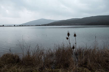 Lake grey landscape. A sad mood. Depression is a longing concept. Gray-blue autumn landscape. It's snowing through a hazy haze. Natural background. Beautiful silvery clouds. Journey to the lakeの写真素材