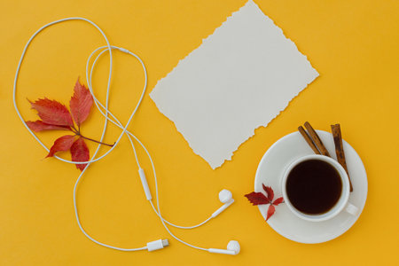 Headphones coffee flat layout. The concept of music, relaxation and free time. Red yellow background, coffee with cinnamon. Warm autumn mood. Mockup is a white sheet of paper. Copy space. Top viewの写真素材