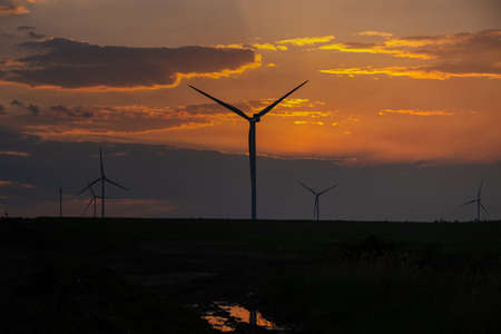 Wind turbines at sunset. Wind turbines in the orange sky. Rural areas with renewable energy sources. The concept of environmental safety green energy. Landscape with windmills. Sustainable developmentの写真素材