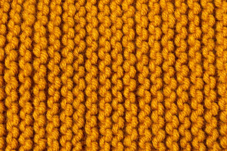 Knitted texture background. Hand-knitted wool. Macrophotography of a thread drawing. Orange pastel texture of sweaters, pullovers, cardigans. Abstract natural background. Comfort autumn warmth conceptの写真素材