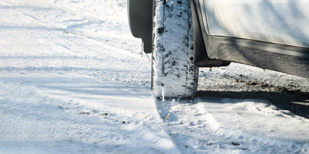 Car wheels snow close-up. Driving on a winter road. Winter tires shooting from a lower angle. The concept of travel, traffic safety, traveling by car. Bright sunny landscape. Snow sparkles in the sunの写真素材
