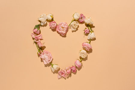 A heart of pink roses. Minimalistic floral arrangement on a beige background. View from above. A flat romantic layout of delicate fragrant roses. The concept of love, Valentine's Day, Mother's Day.の写真素材