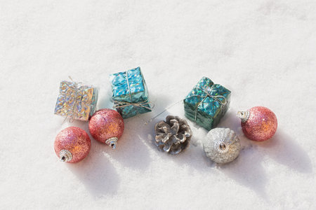 Snow Christmas decorations. Silver blue pink shiny balls gifts lie on the snow and sparkle. The concept of a holiday, magic, congratulations. Horizontal snow banner in bright sunlight. Happy New Yearの写真素材