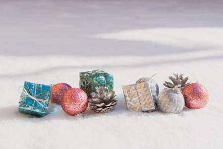 Snow Christmas decorations. Silver blue pink shiny balls gifts lie on the snow and sparkle. The concept of a holiday, magic, congratulations. Horizontal snow banner in bright sunlight. Happy New Yearの写真素材