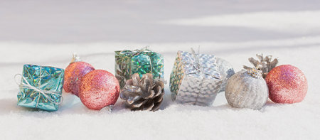 Snow Christmas decorations. Silver blue pink shiny balls gifts lie on the snow and sparkle. The concept of a holiday, magic, congratulations. Horizontal snow banner in bright sunlight. Happy New Yearの写真素材