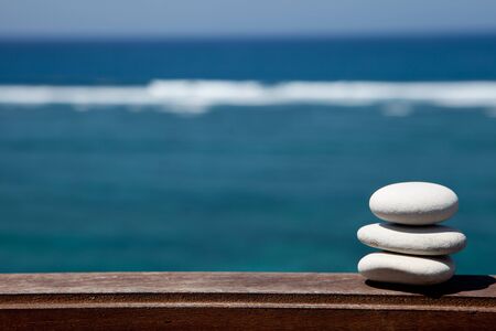 Stack of pebble stones at the beach on a wooden surfaceの写真素材