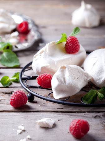 Meringues with fresh berries and mint leaves on a wooden backgroundの写真素材