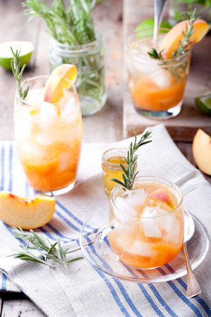 Peach and rosemary fizz cocktail on a wooden background.の写真素材