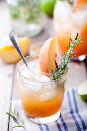 Peach and rosemary fizz cocktail on a wooden background.の写真素材