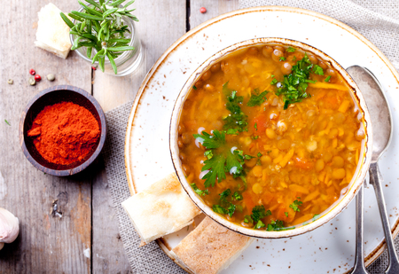 Lentil soup with smoked paprika and bread in a ceramic bowl on a wooden backgroundの写真素材