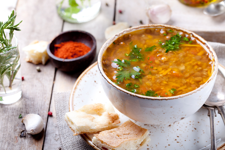 Lentil soup with smoked paprika and bread in a ceramic bowl on a wooden backgroundの写真素材