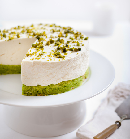 Pistachio cheesecake, mousse cake with nuts decoration on a white plateの写真素材