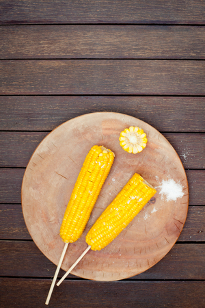 Boiled sweet corn cobs with salt on a wooden backgroundの写真素材