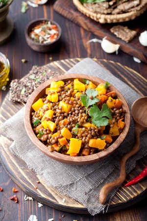 Lentil with carrot and pumpkin ragout in a wooden bowl on a wooden backgroundの写真素材