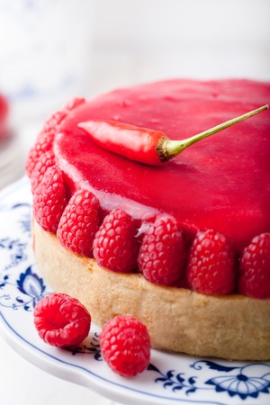 Raspberry and roast bell pepper mousse cake, cheesecake with fresh chili pepper on a white wooden backgroundの写真素材