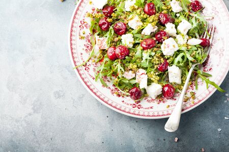 Salad with arugula, cherries and goat cheese on a blue backgroundの写真素材