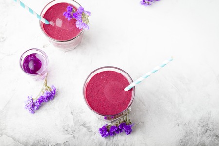 Blueberry, blackberry, honeysuckle, honeyberry smoothie with violet syrup and acai berry powder on a stone background.の写真素材