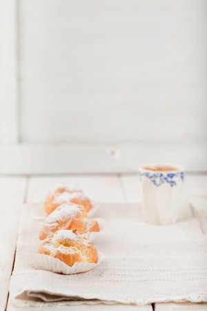 Profiteroles, choux with a custard cream, creme anglaise, whipped cream, dessert on a white plate