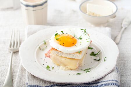 Croque madame, egg, ham, cheese sandwich with a cup of coffee. Traditional French cuisine. Breakfast table.の写真素材