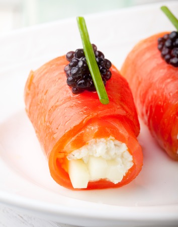 Smoked salmon rolls with cream cheese, cucumber, black caviar and chivesの写真素材