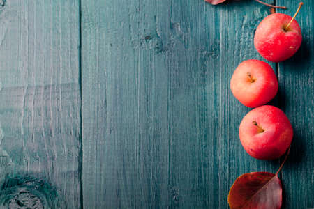 Red apples and leaves on a wooden blue, turquoise backgroundの写真素材