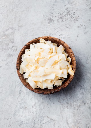 Organic Roasted Coconut Chips Flakes with Sugar and Salt Wooden bowl Stone backgroundの写真素材