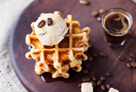 Fresh whole wheat waffles with ice cream, maple syrup and coffee on a wooden backgroundの写真素材
