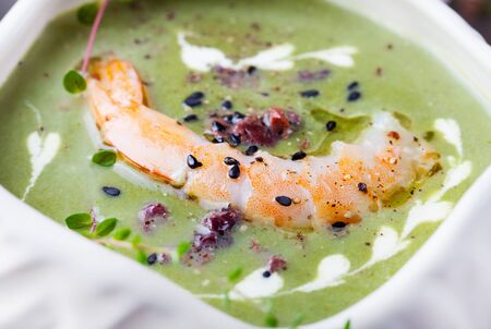 Broccoli, spinach cream soup with shrimp in a white bowls on a wooden board Top viewの写真素材