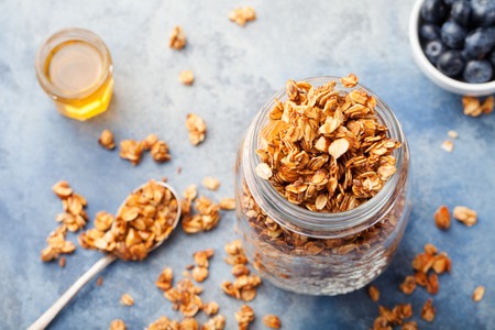 Healthy breakfast Fresh granola, muesli with berries, honey in a glass jar on a stone background Copy spaceの写真素材