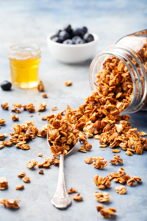Healthy breakfast Fresh granola, muesli with berries, honey in a glass jar on a stone backgroundの写真素材