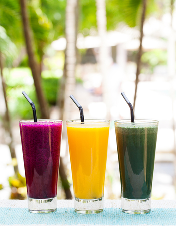 Assortment juices, smoothies, beverages, drinks variety on a outdoor tropical background Copy spaceの写真素材