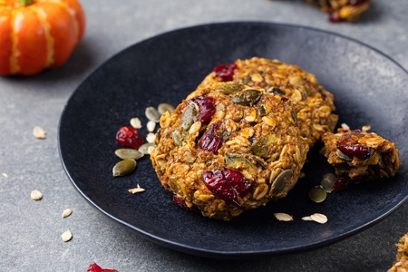 Pumpkin cookies with cranberries and maple glaze on a black plate. Grey stone background.の写真素材