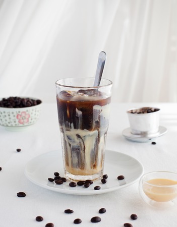 Ice coffee with condensed milk, traditional Vietnamese, Thai coffee with coffee beans on a white plate backgroundの写真素材