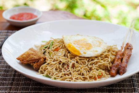 Nasi Goreng with fried egg, chicken Indonesian stir fried noodles Outdoor background.の写真素材