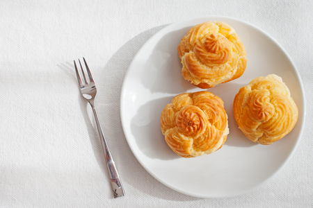 Profiteroles, choux with a custard cream, creme anglaise, whipped cream, dessert on a white plate...