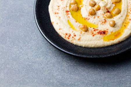 Hummus, chickpea dip, with spices and pita, flat bread in a black plate on grey stone background. Copy space Top viewの写真素材
