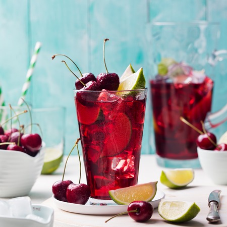 Cherry cola, limeade, lemonade, cocktail in a tall glass on a white, turquoise background Copy space
